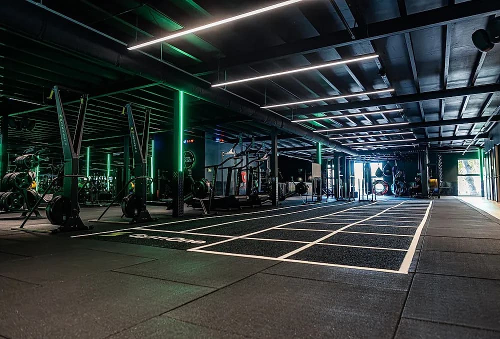 HYROX-sprintbaan bij GymOne Alkmaar met GymOne-vloerlogo en groene LED-lijnen