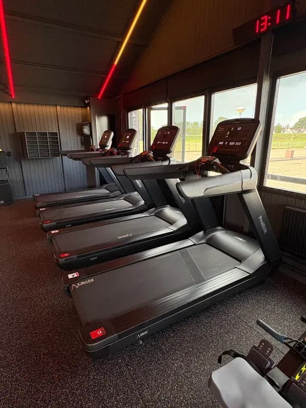 Cardiozone met een rij loopbanden langs grote ramen